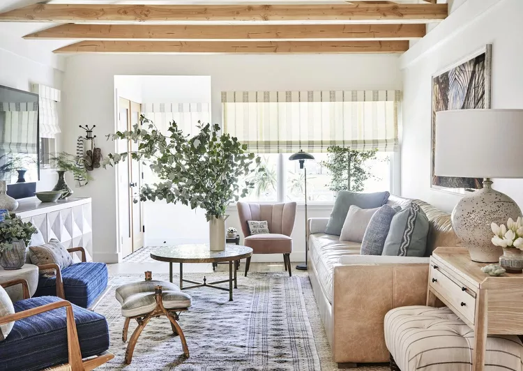 A light living room with a tan sofa, blue chairs, and a round table.